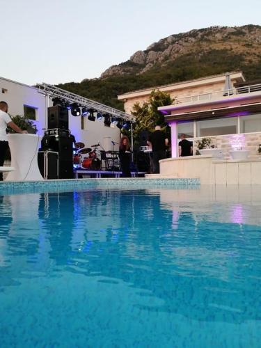 a blue swimming pool with a band in the background at Villa Eagle Eye Montenegro in Kotor