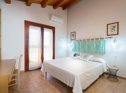 een witte slaapkamer met een bed en een tafel bij Edomat in Monserrato