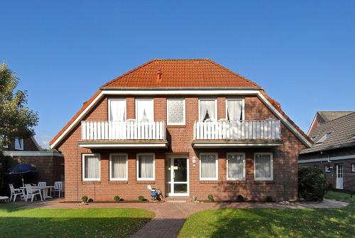 a brown brick house with white balconies on it at Friesenmeer Apartment in Bensersiel