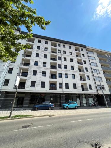 two cars parked in front of a large white building at Poppy in Bijeljina