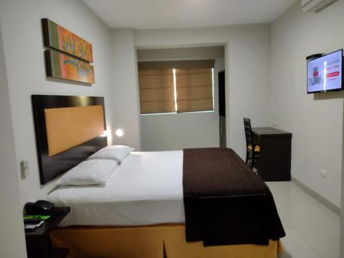 a bedroom with a large bed and a desk at Intiotel Piura in Piura