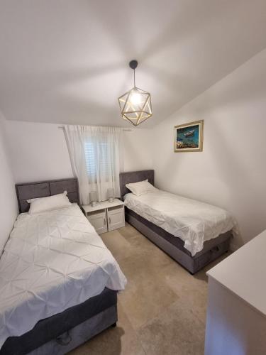 a bedroom with two beds and a chandelier at Apartments Bagić in Vir