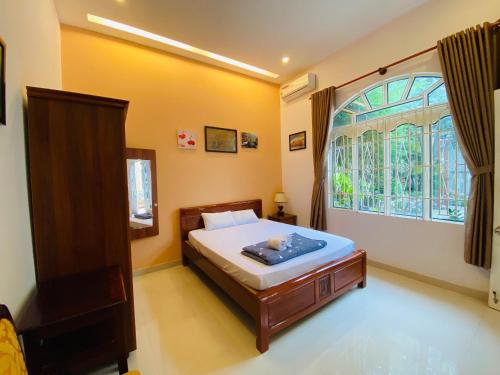 Un dormitorio con una cama y una ventana grande. en Biệt Thự Villa Hai Nam -Vung Tau-G8 Bau Sen 08, en Vung Tau