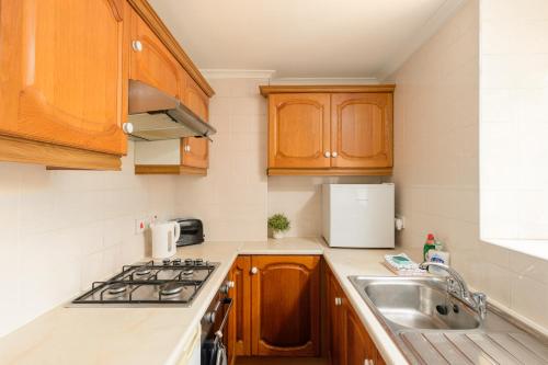uma cozinha com armários de madeira e um lavatório em Cosy Dean Village Studio em Edimburgo