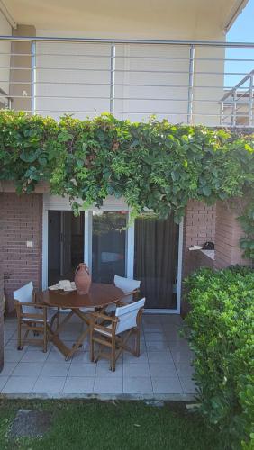 a patio with a table and chairs under a green hedge at Evita Maisonette, Elegant Beachfront apt, Polychrono in Polykhrono