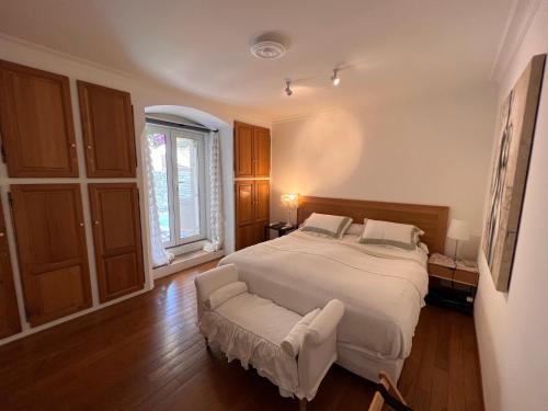 una camera con un grande letto bianco e una sedia di Les Grimaldines - Maison d'Hôtes a Cagnes-sur-Mer
