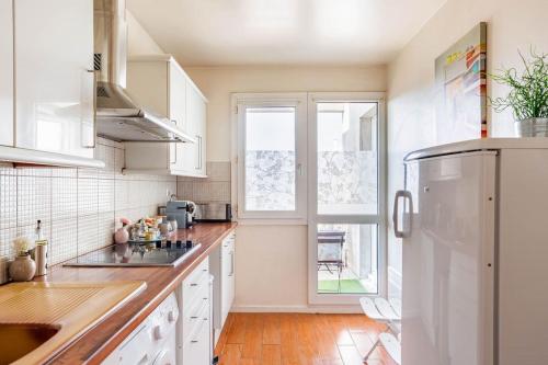 uma cozinha com electrodomésticos brancos e uma janela em Appartement à 10 minutes du centre de Paris avec le RER B em La Courneuve
