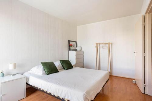 a bedroom with a white bed with green pillows at Appartement à 10 minutes du centre de Paris avec le RER B in La Courneuve