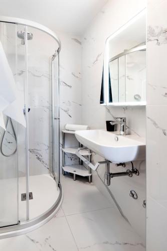 a white bathroom with a sink and a shower at Guesthouse Santin in Rovinj