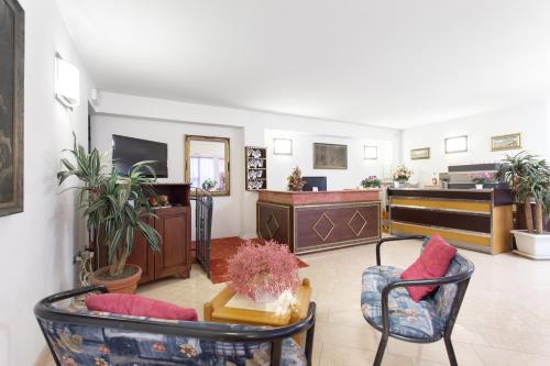 een woonkamer met 2 stoelen en een televisie bij Hotel Residence Des Bains in Cesenatico