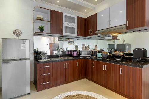 a kitchen with wooden cabinets and a white refrigerator at Villa Estella ☆ Seminyak Kuta - Private Pool in Seminyak