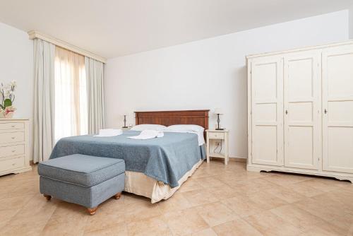 a white bedroom with a bed and a chair at Salvapiano Holiday Ranch in Riotorto