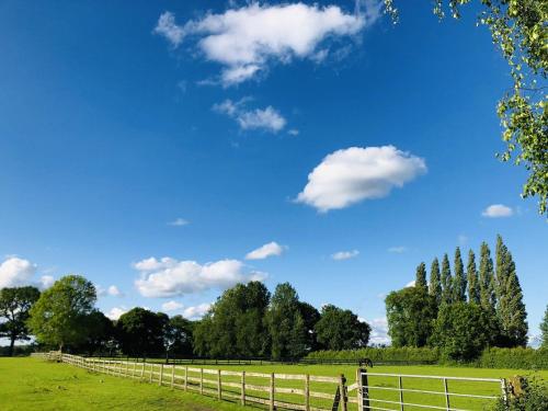 a fence in a field with a blue sky at The Hoglets in Goostrey