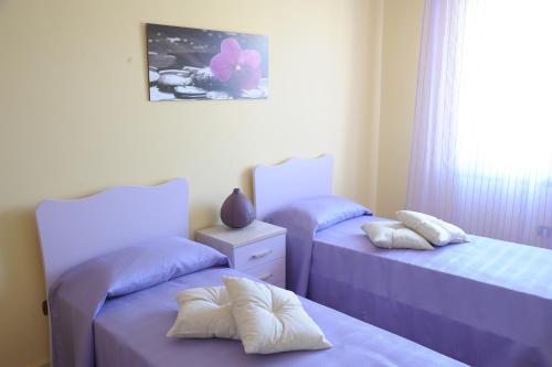 マンドゥーリアにあるB&B Abitazione Sandraの紫色のシーツと枕が備わる客室内のベッド2台