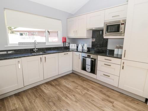 a kitchen with white cabinets and black counter tops at Lodge 32 in Newcastle upon Tyne