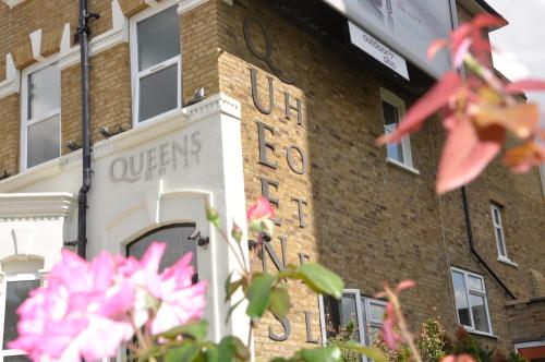 a brick building with a sign on the side of it at Queens Hotel in London