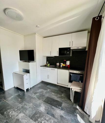 a kitchen with white cabinets and a tiled floor at Pension des Draizes in Neuchâtel
