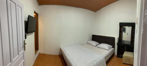 a bedroom with a bed and a flat screen tv at Dieng Plateau Guest House in Diyeng