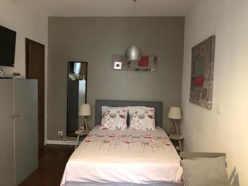 une chambre avec un lit avec des draps blancs et des oreillers dans l'établissement Studio Saint-Placide, à Paris