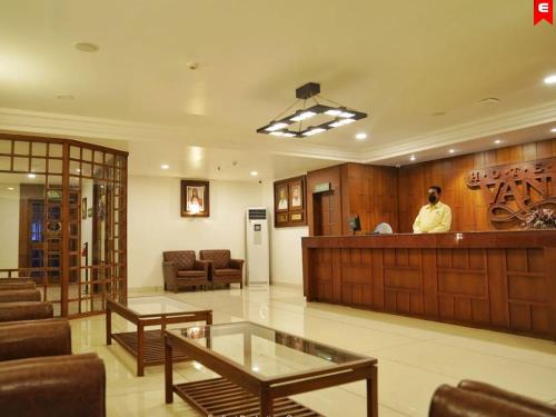 a man standing at a reception desk in a lobby at Hotel Vani in Changanācheri