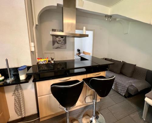 a kitchen with a counter and two bar stools at Pension des Draizes in Neuchâtel