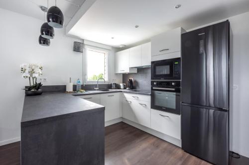 a kitchen with white cabinets and a stainless steel refrigerator at La Canopée By Plaza in Serris
