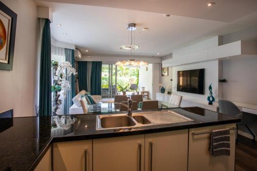 a kitchen with a sink and a living room at Blue Bay Apartments in Sint Michiel