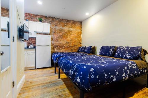 ein Schlafzimmer mit einem Bett mit blauer Bettwäsche und einer Ziegelwand in der Unterkunft Studios in New York in New York