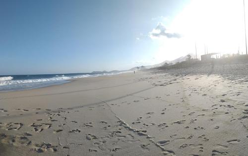uma praia com pegadas na areia e no oceano em Pousada das Casuarinas em Saquarema