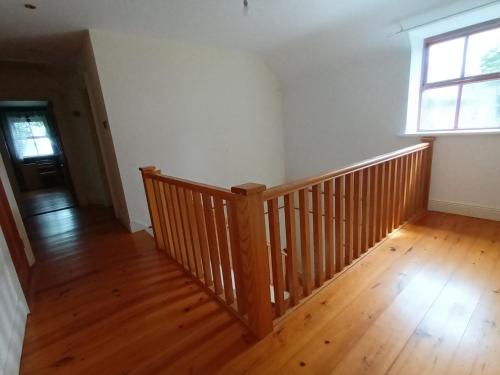 an empty room with a wooden staircase and a window at Clós Na Feirme in Galway