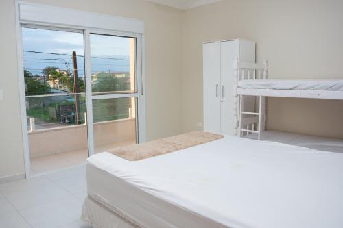 - une chambre blanche avec un lit et une fenêtre dans l'établissement Sobrado aconchegante apenas 150 m do mar, à Guaratuba