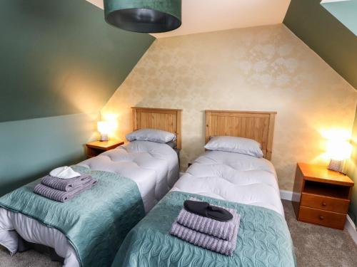 two twin beds in a room with two lamps at Ulla Dhu in Nethy Bridge