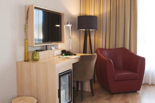 a hotel room with a desk and a chair and a television at Weinhotel Kaisergarten in Alzey