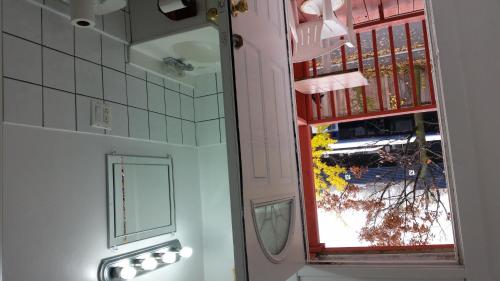 a mirror in a bathroom next to a window at A Voyageur's Guest House in Ottawa