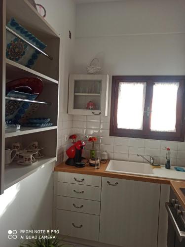 a kitchen with white cabinets and a sink and a window at Fousa Home in Poros
