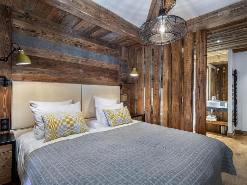 Un dormitorio con una cama y una pared de madera. en Chalet luxueux avec 5 chambres, hammam, cheminée et grande terrasse au cœur de Val d'Isère - FR-1-567-34, en Val dʼIsère