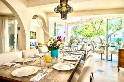 a dining room with a long wooden table with white plates at Casa Coco by Coco B Isla in Isla Mujeres