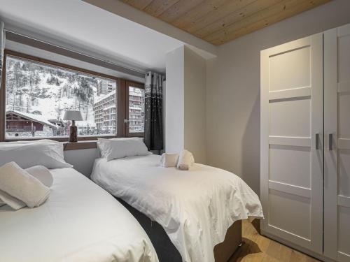 deux lits dans une chambre avec une fenêtre dans l'établissement Duplex rénové avec parking, proche centre et remontées, navette et bus à deux pas - FR-1-567-41, à Val dʼIsère