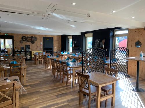 une salle à manger avec des tables et des chaises en bois dans l'établissement hôtel de la grange, à Cossé-le-Vivien
