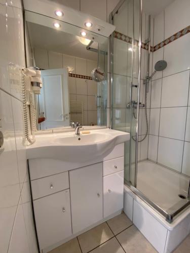 y baño blanco con lavabo y ducha. en Haus Jenny, Wohnung E3b, Sonne rundum en Boltenhagen