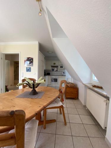 a dining room with a wooden table and a kitchen at Haus Jenny, Wohnung E3b, Sonne rundum in Boltenhagen