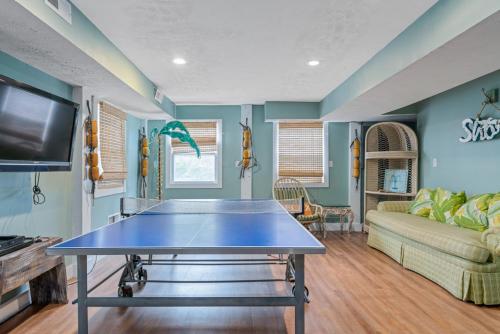 a ping pong table in a living room with a couch at Fairwinds by Oak Island Accommodations in Caswell Beach