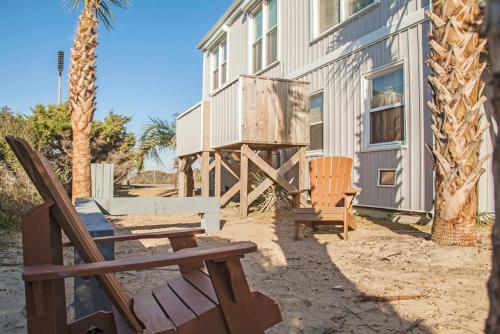 a patio with two chairs and a building at Fairwinds by Oak Island Accommodations in Caswell Beach