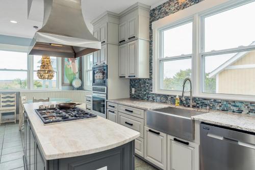 a kitchen with white cabinets and a sink at Fairwinds by Oak Island Accommodations in Caswell Beach
