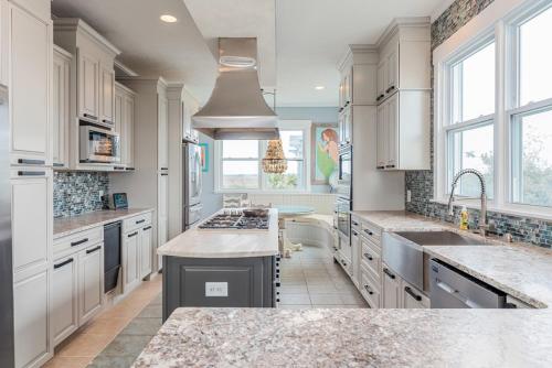 a kitchen with white cabinets and granite counter tops at Fairwinds by Oak Island Accommodations in Caswell Beach