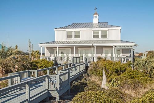 a white house with a lighthouse on the beach at Fairwinds by Oak Island Accommodations in Caswell Beach