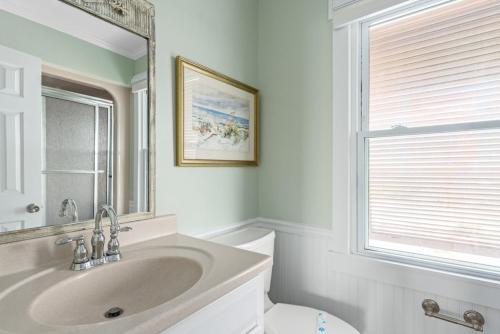 a bathroom with a sink and a toilet and a mirror at Fairwinds by Oak Island Accommodations in Caswell Beach