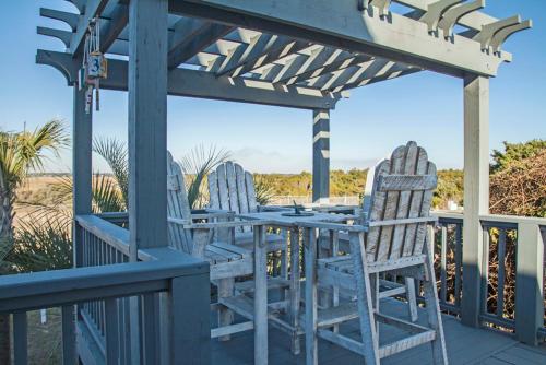a porch with two chairs and a table on a deck at Fairwinds by Oak Island Accommodations in Caswell Beach