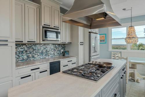a kitchen with white cabinets and a stove top oven at Fairwinds by Oak Island Accommodations in Caswell Beach