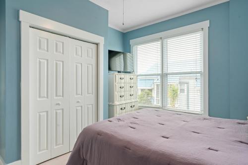 a bedroom with a bed with blue walls and a window at Fairwinds by Oak Island Accommodations in Caswell Beach